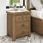 Oak bedside table with 4 drawers in large size is shown in a room setting next to a bed