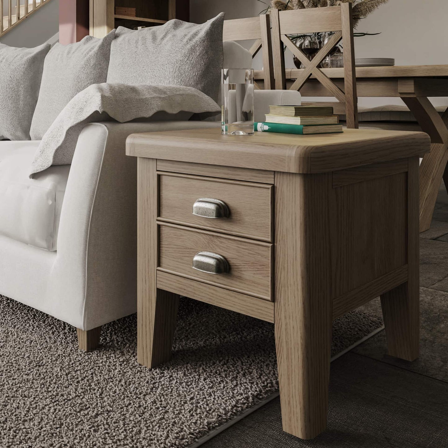 Oak lamp table with 2 drawers is shown in a room setting serving as an end table for the sofa. There is a glass of water and books on the top