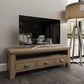 Standard oak TV stand with a shelf and 3 drawer storage shown in a room setting with TV and media box in place