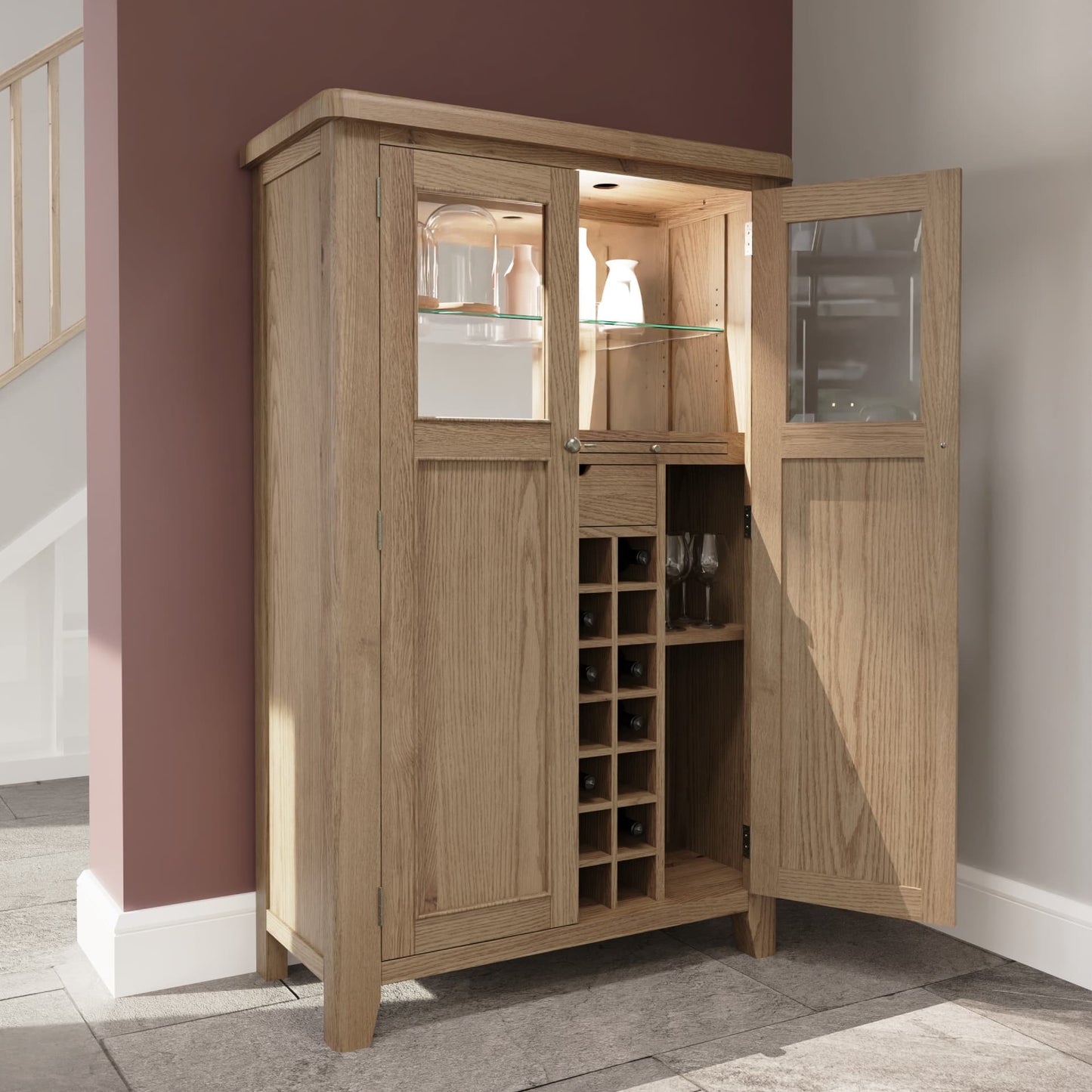 Tall oak drinks cabinet is shown in a room setting half open revealing wine rack, shelves, mirrored back and LED lights inside