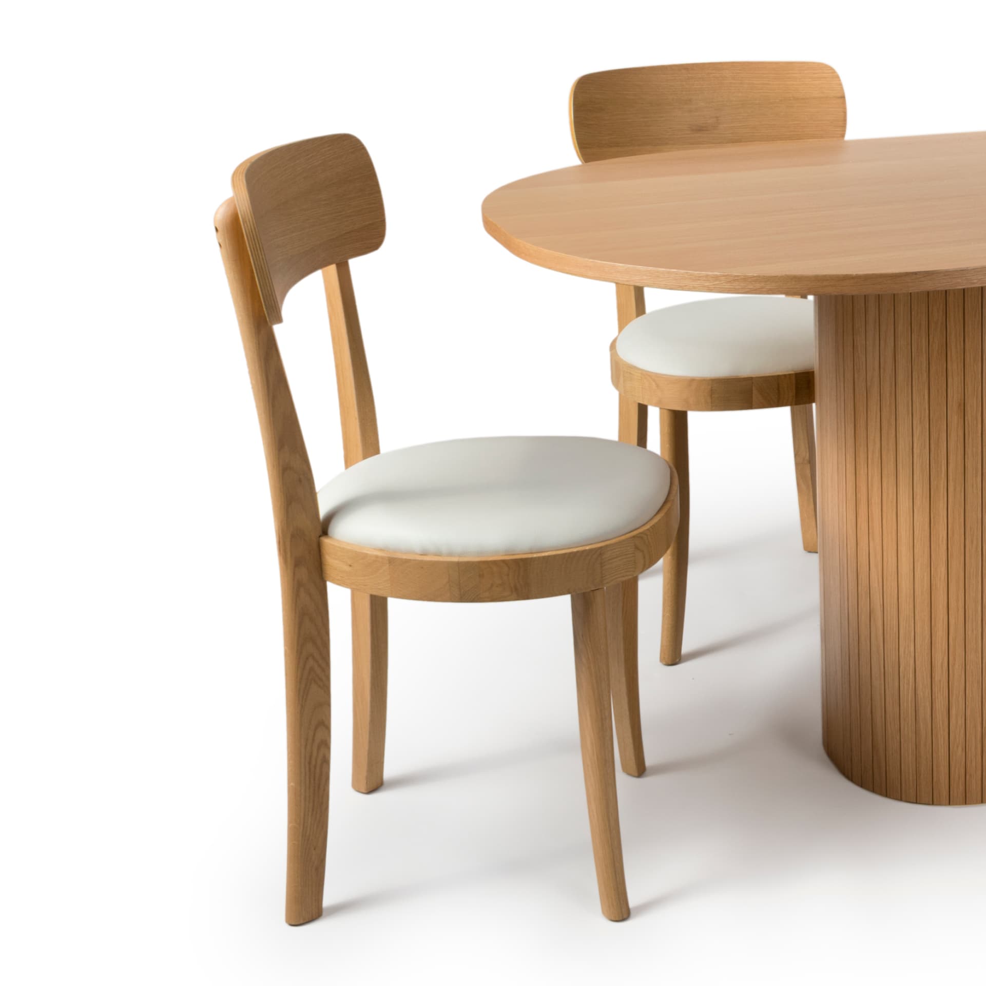 Oak dining chair with faux leather padded seat shown on white background next to an oak table