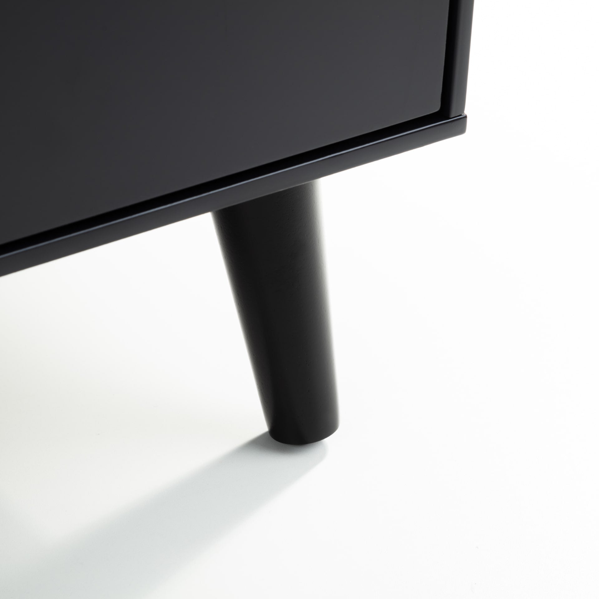 Close view of the sides, edges and leg of the black bedside table