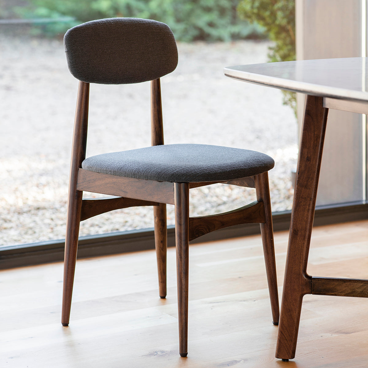 Minimalist elegant dining chair with tapered wooden legs and padded seat and backrest in room setting