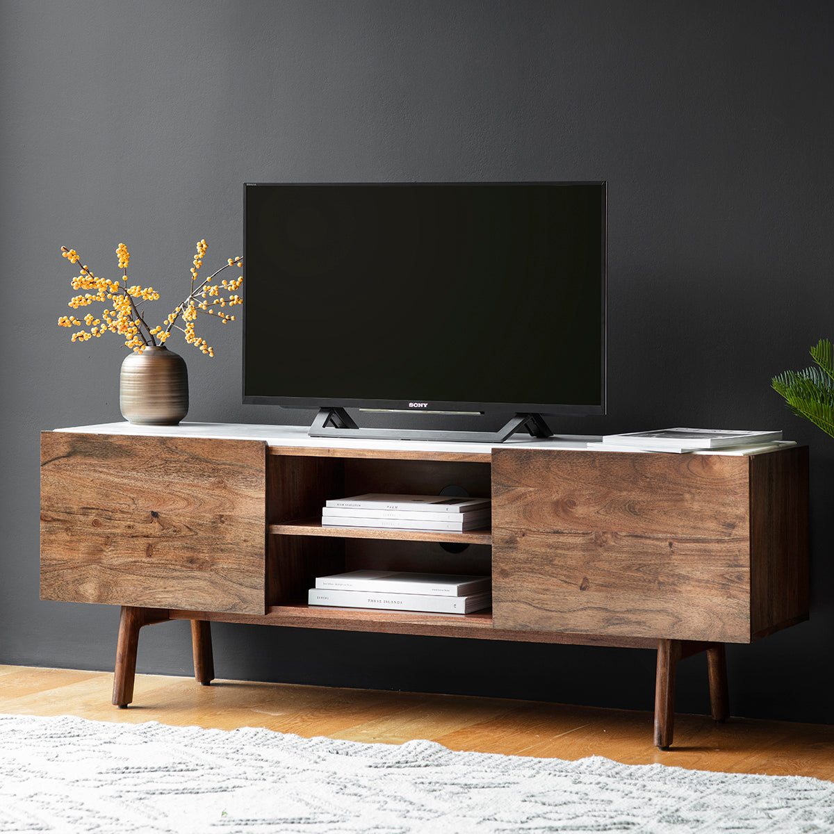 Wooden TV unit with white marble top and storage in a room setting with TV and decor 