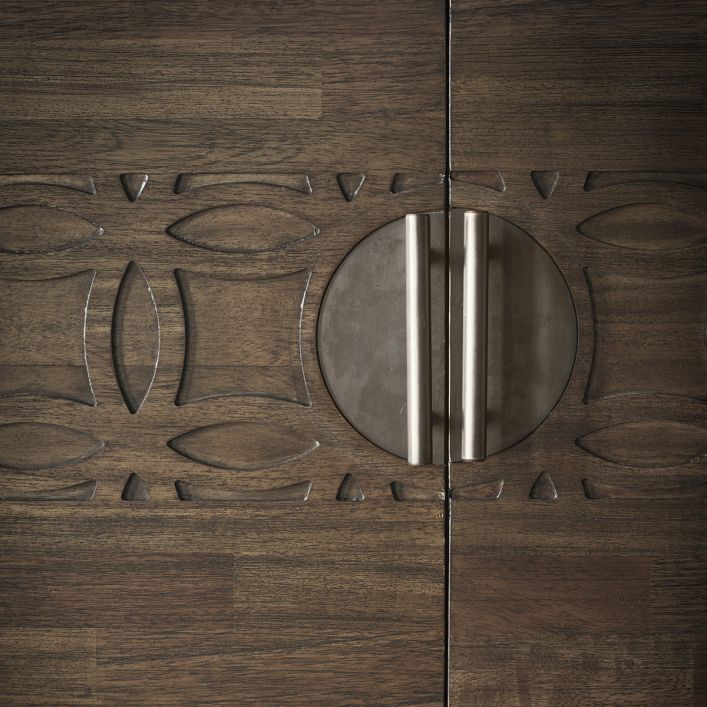 Zoomed view on cabinet door handles, blind fret carving decor and mixed wood veneer surfaces of the doors