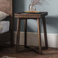 Stunning and elegant end table pictured next to the bed. Featuring tray like table top with carved sides and cross legged structure, the table is decorated with vases and flowers.