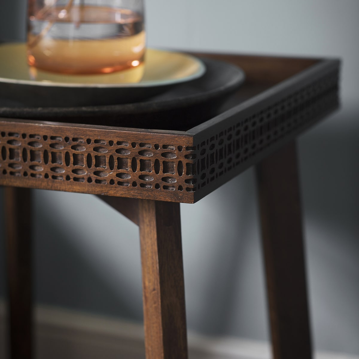 Close-up look at blind fretwork decorating the sides of the tray-like table top of the side table and legs